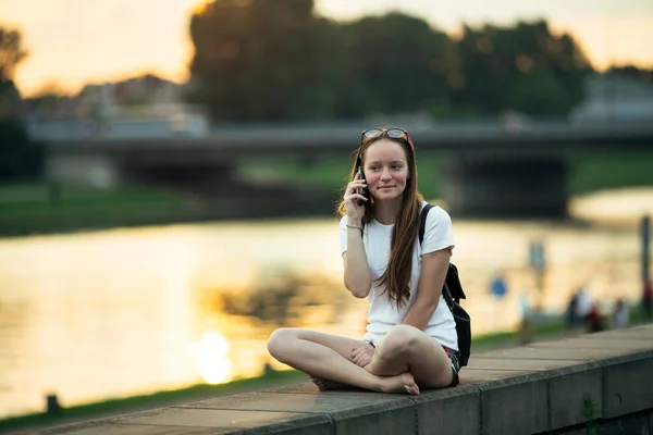 Uma Menina Falando Telefone Sentado Orla Cidade Durante Pôr Sol Imagem De Stock