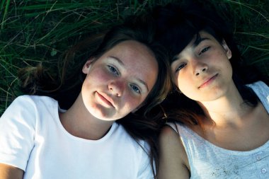 Yukarıdan iki kız arkadaşın portresi yeşil çimlerin üzerinde yatıyor.. 