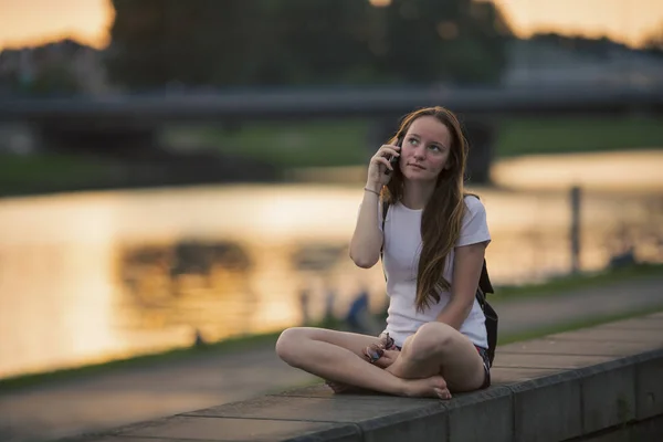 Uma Rapariga Falar Telemóvel Enquanto Senta Beira Mar Cidade Fotografias De Stock Royalty-Free