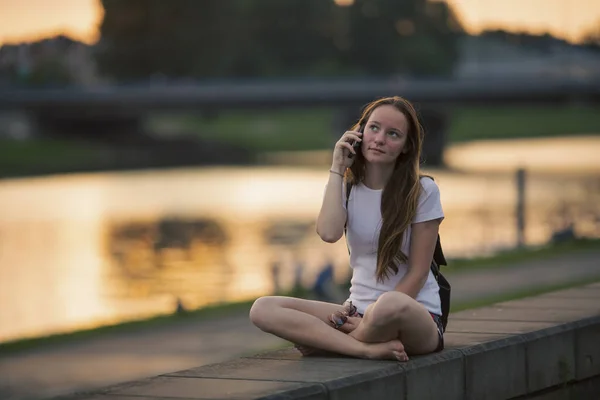 Una Ragazza Che Parla Cellulare Mentre Seduta Sul Lungomare Della Foto Stock Royalty Free