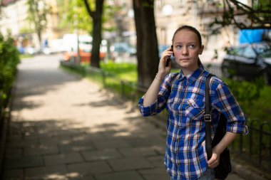 Şehir parkında cep telefonuyla konuşan genç bir kız..