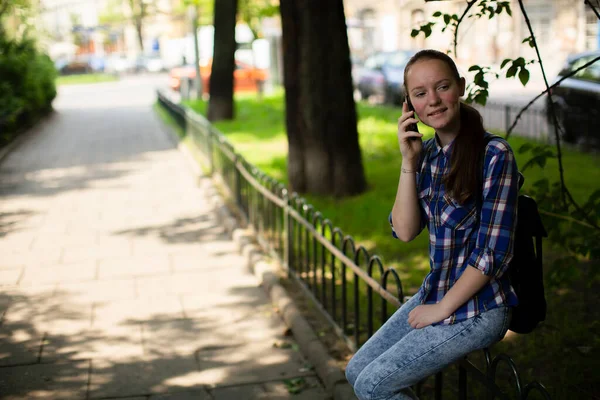 街の路地に座っている間に10代の女の子が携帯電話で話している — ストック写真