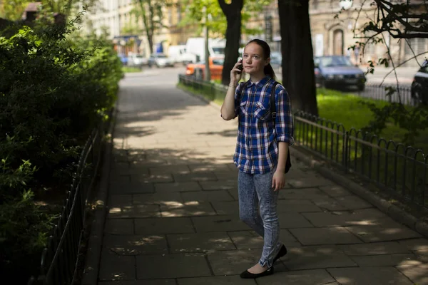 소녀가 도로변을 걷다가 휴대폰으로 이야기를 — 스톡 사진