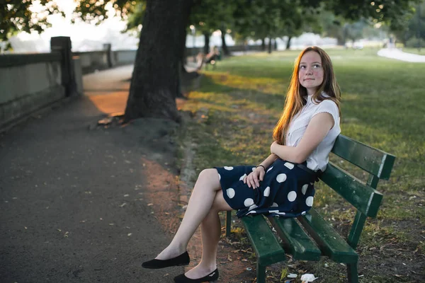 金髪の女の子が夕日の夏の路地に座っている ストックフォト