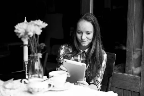 女の子がカフェにタブレットを持って座っている 白黒写真 — ストック写真