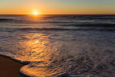 Foamy surf during a stunning sunset on the Atlantic ocean portugal coast.   