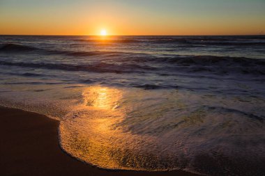 The foamy surf during a stunning sunset on the Atlantic coast.  