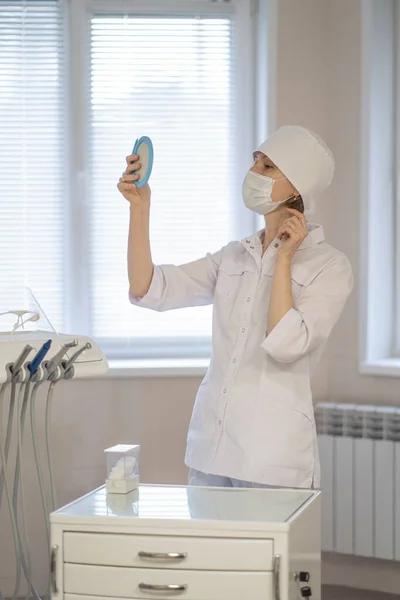 一位女牙医正在镜子前打扮自己 — 图库照片