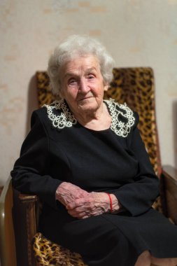 Yaşlı bir kadın evinde bir koltukta oturuyor.. 