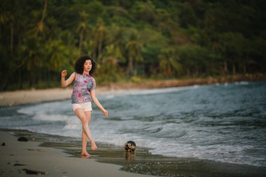 Genç bir kadın denizin sörf çizgisinde neşeyle geziniyor.. 