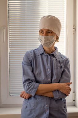 Hastanede mavi üniformalı ve maske takan bir kadın doktor var..