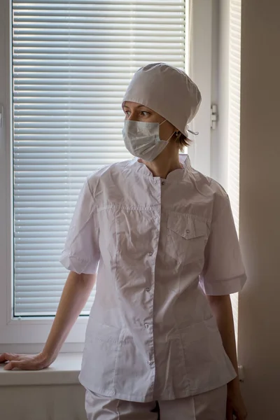 Μια Γυναίκα Γιατρός Που Φοράει Μάσκα Στέκεται Κοντά Στο Παράθυρο — Φωτογραφία Αρχείου
