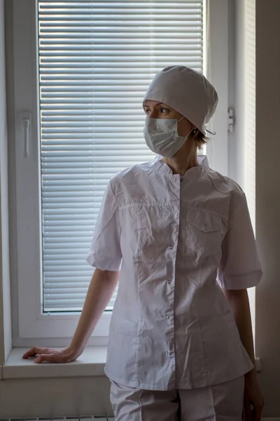 Una Enfermera Vestida Con Una Mascarilla Para Cerca Una Ventana — Foto de Stock