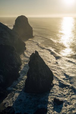 Günbatımında Atlantik Okyanusu 'nda kayalıkların ve sörfün görüntüsü, Portekiz. 