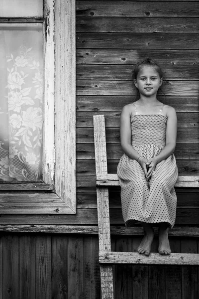 Pikkutyttö Istuu Puutikkailla Kylän Talossa Musta Valkoinen Kuva — kuvapankkivalokuva