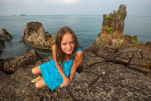 10代の少女が海岸の岩の上に座っている ストックフォト
