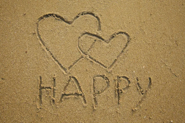 Zwei Herzen Und Die Aufschrift Happy Ist Auf Den Sand lizenzfreie Stockbilder