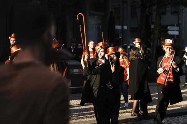 PORTO, PORTUGAL - 3 Mayıs 2022: Cortejo Queima das Fitas sırasında Portekizli üniversite öğrencilerinin yıllık şenliği. Mezunlar bir silindir şapka ve baston takıyorlar. İkisi de fakültenin renginde..