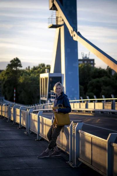 Uma Turista Feminina Com Uma Mochila Amarela Fica Uma Ponte Imagens De Bancos De Imagens Sem Royalties