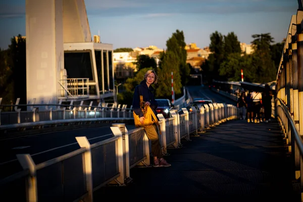 Жінка Туристка Жовтим Рюкзаком Стоїть Мосту Під Час Заходу Сонця Ліцензійні Стокові Фото