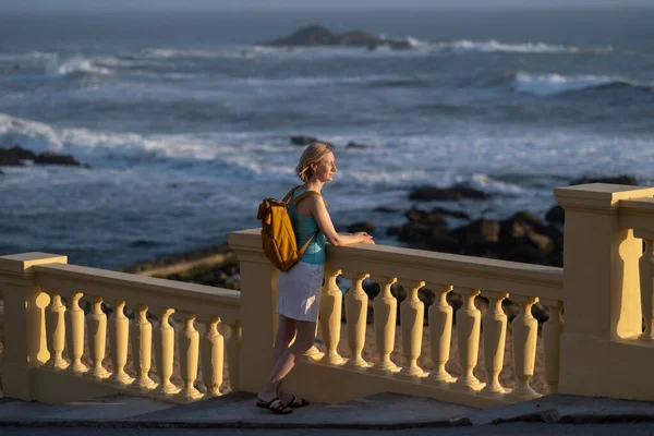 一个背着背包的女人站在海边的长廊上 — 图库照片