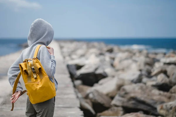 Uma Mulher Encapuzada Coloca Uma Mochila Enquanto Está Cais Oceânico Fotos De Bancos De Imagens