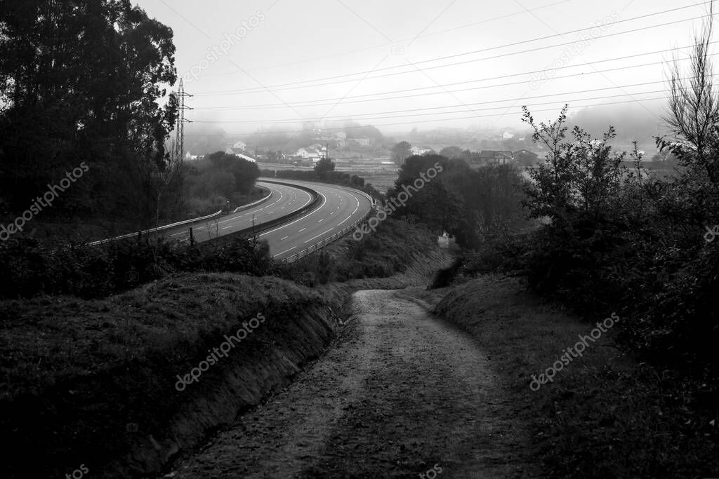 A country road near the highway. Way of the Camino de Santiago, Galicia, Spain. Black and white photo.