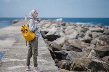 Okyanus rıhtımında sırt çantalı bir kadın turist.