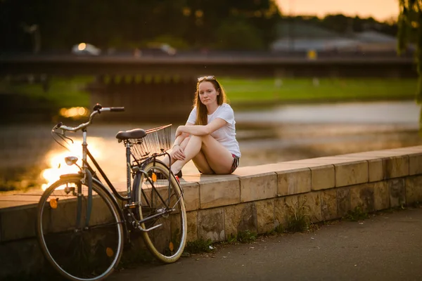 Flicka Med Cykel Sitter Flodstranden Solnedgången — Stockfoto