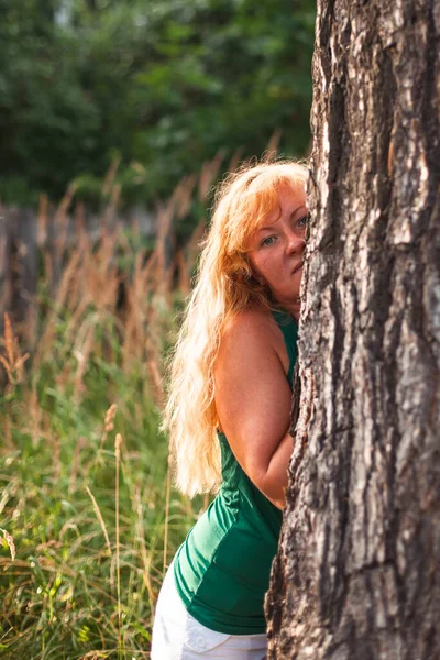 一位金发碧眼的女人在公园的松树旁 — 图库照片