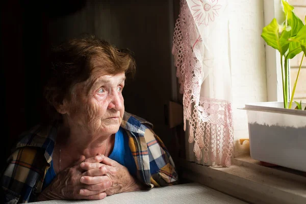 Samotna Staruszka Patrzy Przez Okno Zdjęcie Stockowe