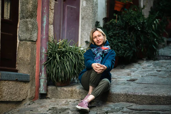 女性は古いヨーロッパの都市の狭い通りの階段に座っています ストックフォト
