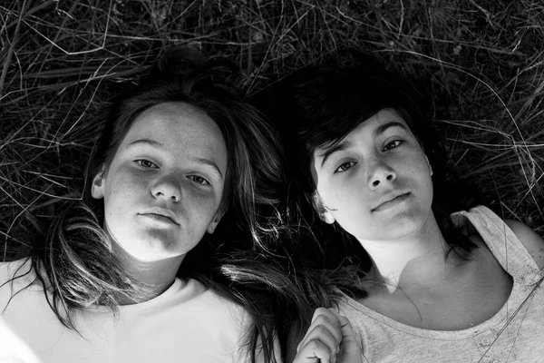 Two Girls Lying Grass Black White Portrait lizenzfreie Stockfotos