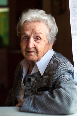 Masada oturan yaşlı bir kadın portresi.