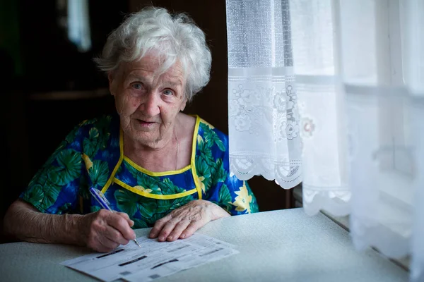 Old Woman Fills Out Receipts Utilities — Stock Fotó