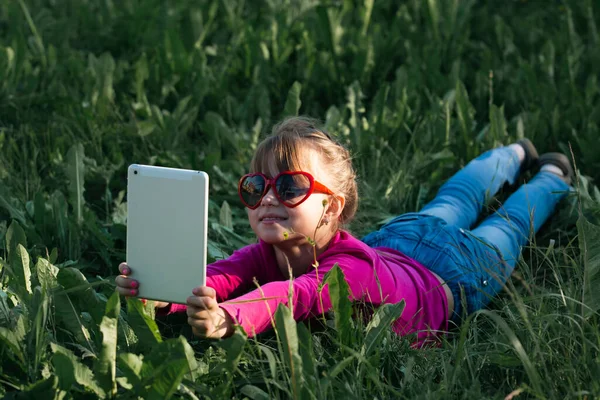 Little Girl Takes Selfies Her Tablet While Lying Green Grass — Stock Photo, Image