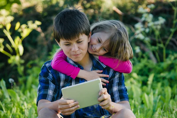 Guy His Little Sister Watching Something Tablet Sitting Grass Park Stockbild