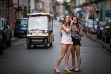 Cute teengirls girlfriends eat m in the middle of the street.