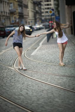 Two pretty girls girlfriends walk on the streetcar rails.