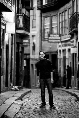 A handsome young man on the streets of an old European city. Black and white photo.