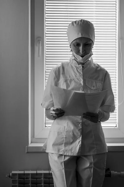 病院の読書記録の窓には女医が立っている 白黒写真 — ストック写真