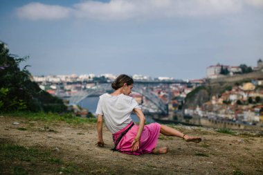 Portekiz, Porto 'daki Dom Luis Köprüsü' nün önündeki Douro Nehri kıyısında dans eden bir kadın..