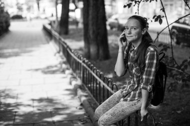 Parkta akıllı telefondan konuşan genç bir kız. Siyah beyaz fotoğraf.