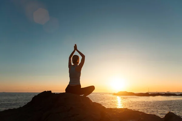 日落时分在海滨站在荷花位置的瑜伽女子的轮廓 — 图库照片