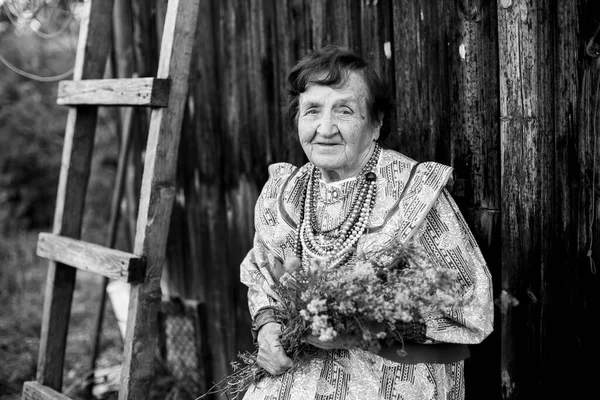 Portrait of a Slavic old woman in the village outdoor. Black and white photo