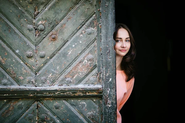Una Hermosa Chica Mira Por Detrás Una Antigua Puerta —  Fotos de Stock