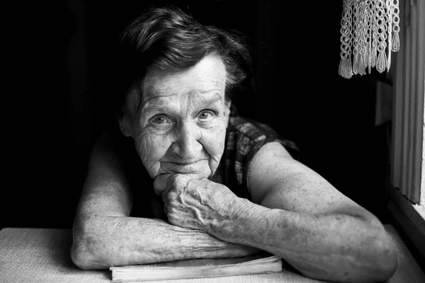 一个老年妇女坐在房子桌子旁边的画像 黑白照片 — 图库照片
