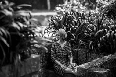 Antik Park 'ta taş bir bankta bir kadın. Siyah beyaz fotoğraf. 