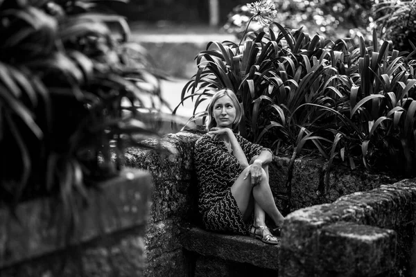 一个女人坐在一个老公园里的石凳上 黑白照片 — 图库照片