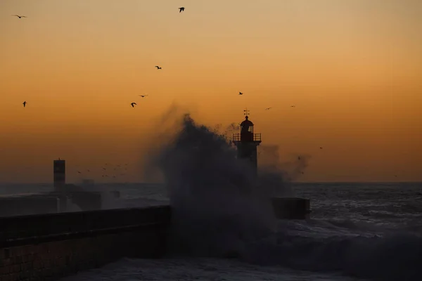 Lighthouse with huge wave during amazing sunset, Porto, Portugal.